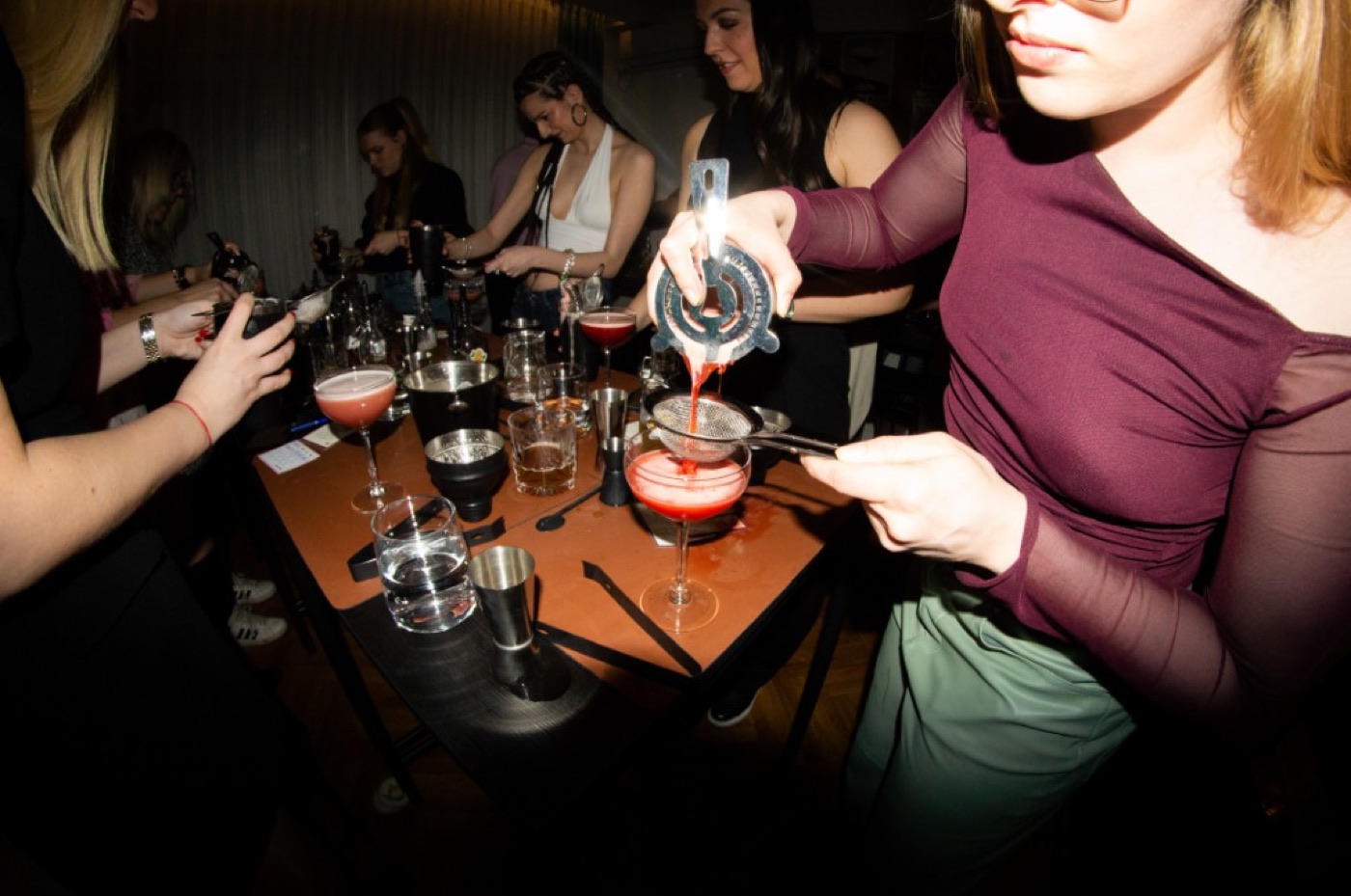 Neon natpis mikstura iznad šanka sa šejkerima i bar alatom
